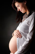 Photo: Pregnant woman over dark background Pregnant woman over dark background