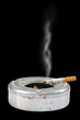 Cigarette on ash tray on black background