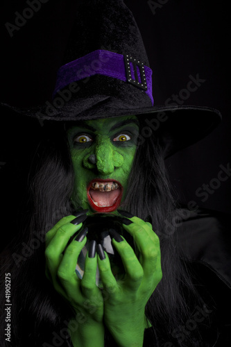 Photo: Witch holding her crystal ball, dark background. Witch holding her crystal ball, dark background.