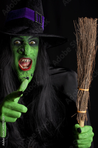 Photo: Witch and her broom stick, black background. Witch and her broom stick, black background.
