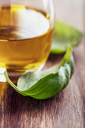 Photo: Basil leaves and olive oil on wooden background Basil leaves and olive oil on wooden background