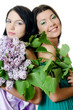 Two girlfriends with flowers of a lilac and green foliage