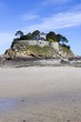 Landscape, seascape with beach and a house on top of a rock.