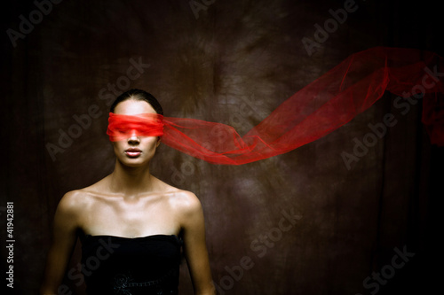 Photo: Beauty brunette with red ribbon on eyes Beauty brunette with red ribbon on eyes