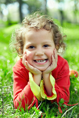 Photo: little girl lying on grass at summer field. a bit dirty hands little girl lying on grass at summer field. a bit dirty hands