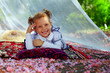 Photo: cute little girl lying in summer arbor among pink petals cute little girl lying in summer arbor among pink petals
