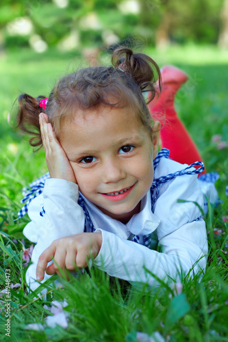 Photo: cute little girl lying on green grass cute little girl lying on green grass