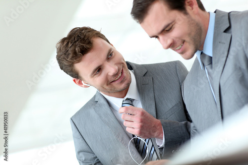 Foto: Business partners working in hallway with electronic tablet Business partners working in hallway with electronic tablet