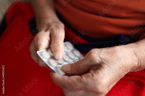 Foto: Close up of old hands with tablets. Close up of old hands with tablets.