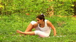 Young woman doing yoga exercise in green park