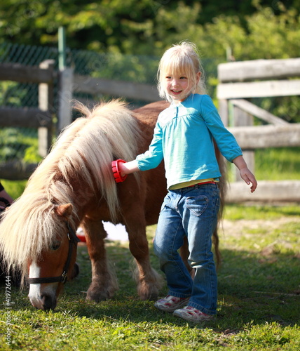 Foto: kleines Mädchen putzt Pony kleines Mädchen putzt Pony