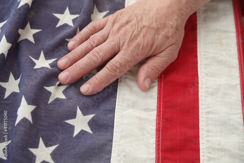 Photo: a man's hand on a very old American flag a man's hand on a very old American flag