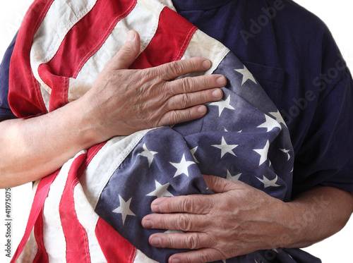 Photo: a veteran holds the American flag close to his body a veteran holds the American flag close to his body