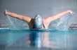 woman swims using the butterfly stroke in indoor pool