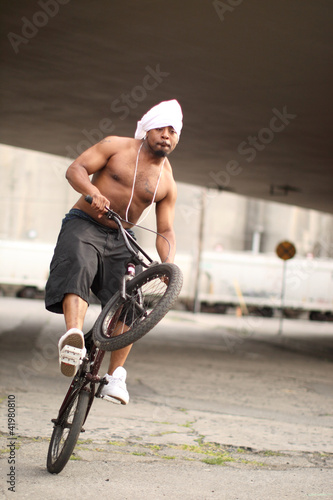 Photo: Young black man on a BMX bicycle. Young black man on a BMX bicycle.