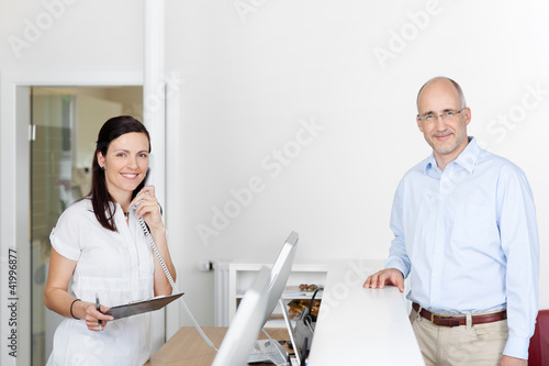 Foto: arzthelferin und patient an der rezeption arzthelferin und patient an der rezeption
