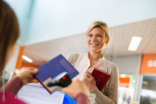 Photo: girl returning book to librarian in library girl returning book to librarian in library