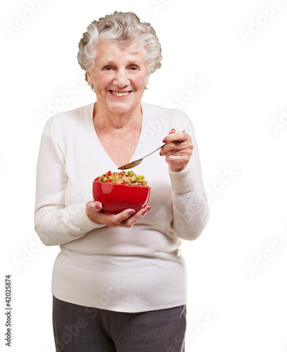 Foto: portrait of senior woman holding a cereals bowl against a white portrait of senior woman holding a cereals bowl against a white
