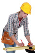 A female carpenter taking measures.