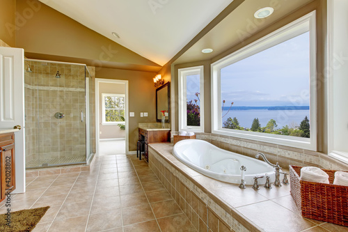 Photo: Large bath tun with water view and luxury bathroom interior. Large bath tun with water view and luxury bathroom interior.
