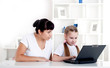 Mom and daughter are working together for a laptop