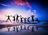 People and dog jumping on the beach. Happiness