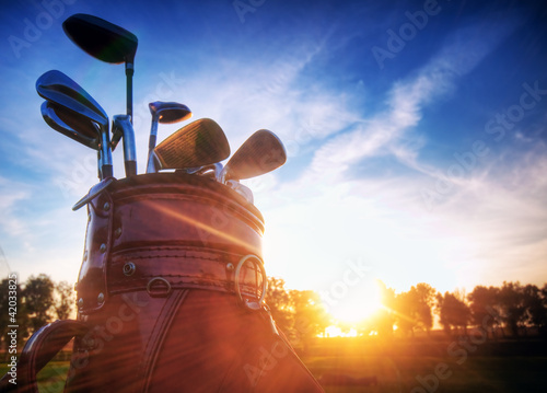 Photo: Golf gear, clubs at sunset on golf course Golf gear, clubs at sunset on golf course