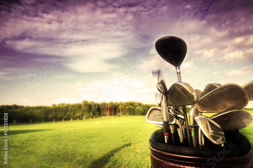 Photo: Golf gear, clubs at sunset on golf course Golf gear, clubs at sunset on golf course