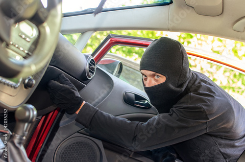 Photo: Thief in the mask breaks the door in the car Thief in the mask breaks the door in the car