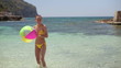Happy woman throwing beach ball into camera lens, slow motion