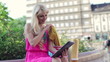 Woman with shopping bags chatting on tablet in city