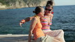 Video: Two happy laughing girls sitting by the sea, tracking shot Two happy laughing girls sitting by the sea, tracking shot