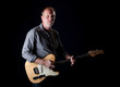 Shadow filled shot of a rugged looking guitar player