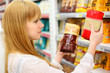 Foto: Blonde girl wearing white shirt compares rice in store Blonde girl wearing white shirt compares rice in store