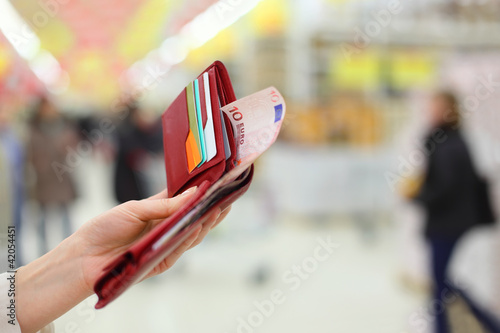 Photo: Woman hand keep red purse with money and credit cards in store; Woman hand keep red purse with money and credit cards in store;