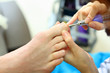 Female hands polish male toes by special machine in beauty salon