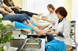 Two women wearing coats practices chiropody taking care of feet