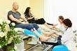 Two women wearing coats practices chiropody taking care of feet