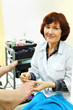 Woman wearing coat practices chiropody taking care of male feet