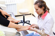Woman wearing white coat makes pedicure for client in salon