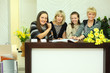 four smiling women sit in reception area with magazines