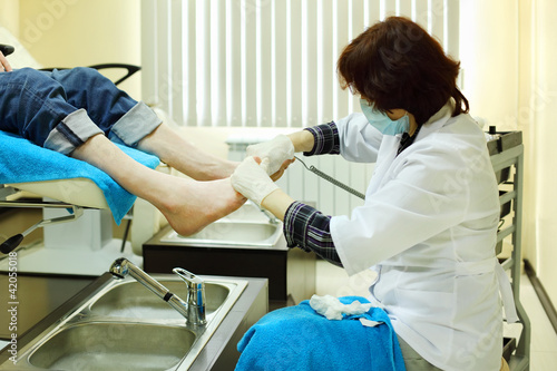 Photo: Woman wearing white coat practices chiropody taking care of male Woman wearing white coat practices chiropody taking care of male