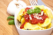 Tortellini with ingredients on wood
