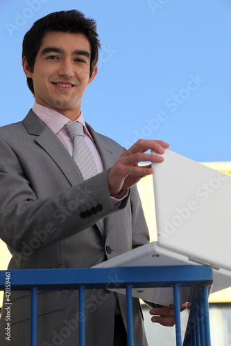 Foto: Businessman using his laptop on a balcony Businessman using his laptop on a balcony