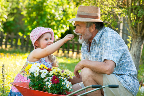 Photo: Happy grandfather with his granddaughter in the garden Happy grandfather with his granddaughter in the garden