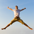 Happy young man jumping against blue sky background