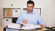 Manager with files at his desk receiving a phone call in his off