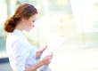 Young beautiful business woman reading newspaper