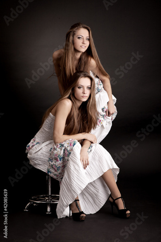 Photo: Two girls twins, isolated on the grey background Two girls twins, isolated on the grey background