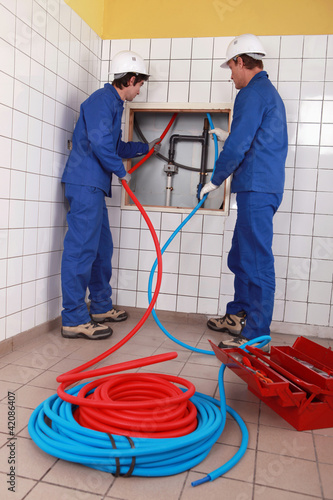 Photo: Plumbers installing new hot and cold pipes Plumbers installing new hot and cold pipes